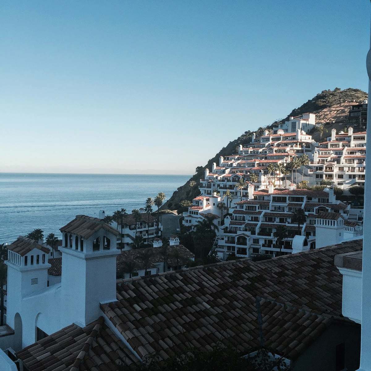tile roof white and brown concrete houses near sea during daytime 23–99 camino de flores